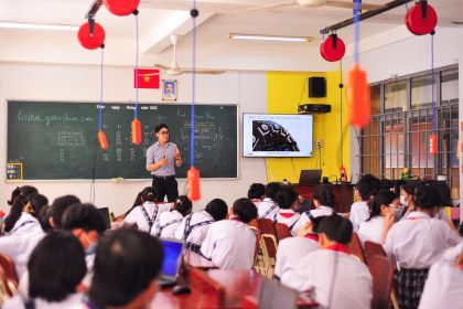 Professor conduz atividade interativa enquanto estudantes acompanham a aula em uma sala de aula.