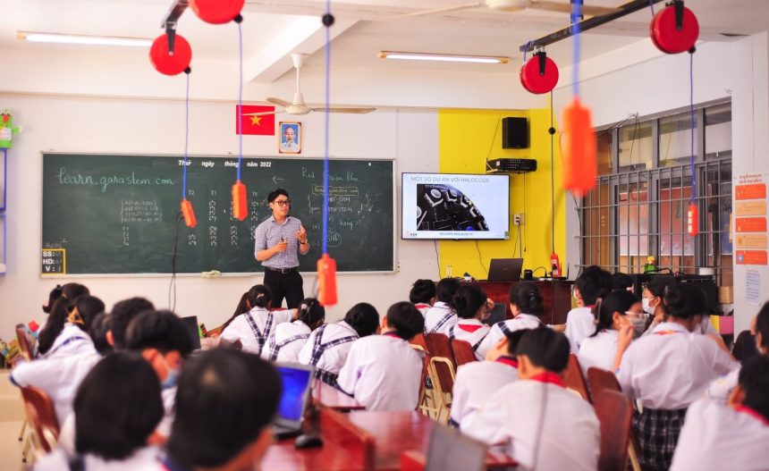 Professor conduz atividade interativa enquanto estudantes acompanham a aula em uma sala de aula.